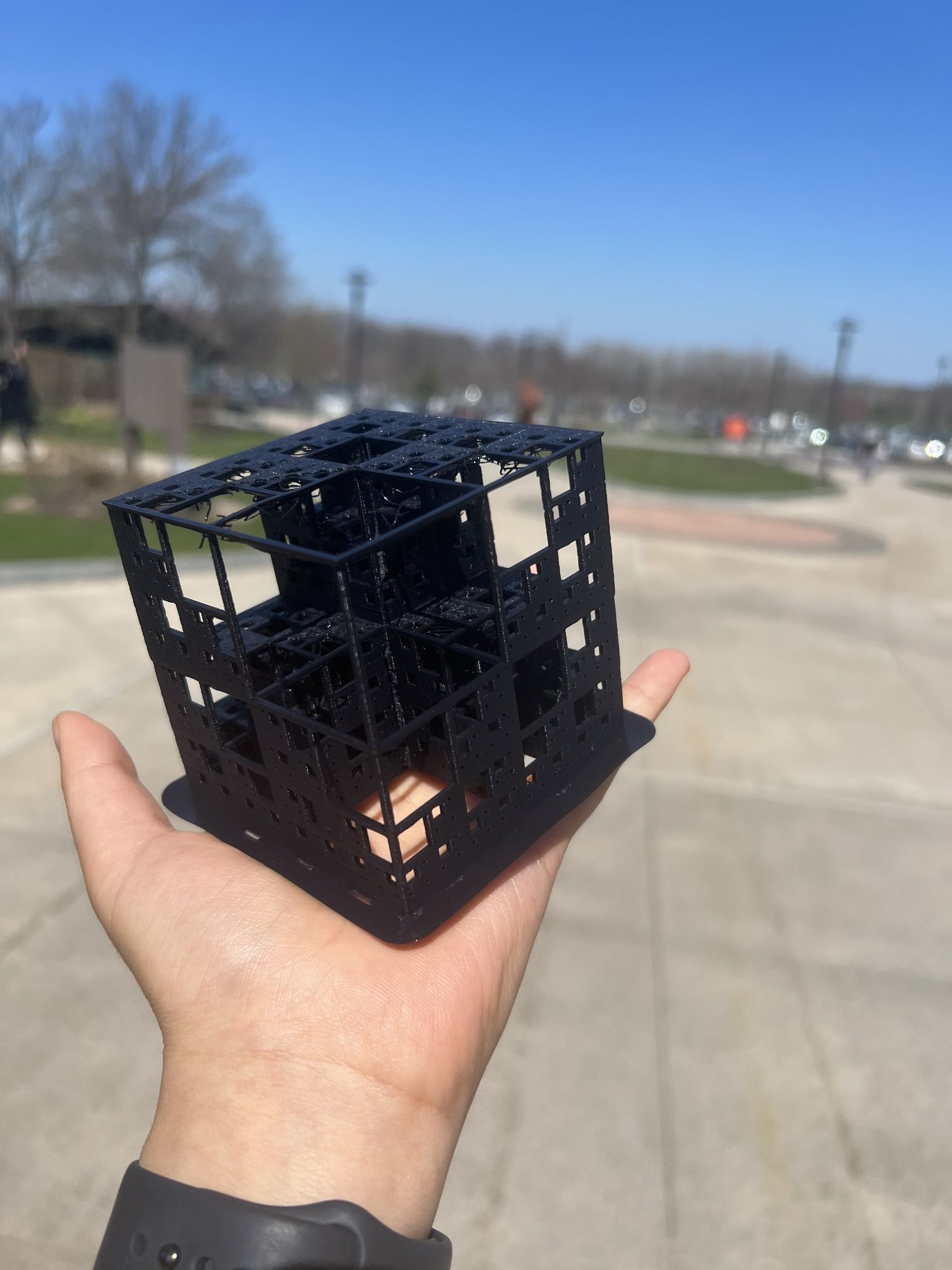 The Recursion Cube as a black 3D print held in a hand